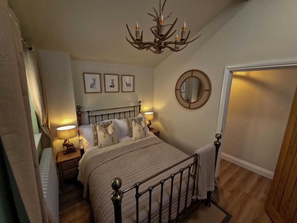 A bedroom with a bed, nightstands, and a chandelier at High Spec 1Bed Cottage in Staindrop