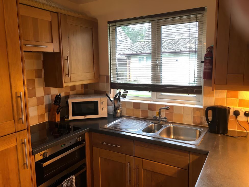 A kitchen with a sink and microwave at Cosy 3 Bedroom House on Cornish estate with pool in St Tudy