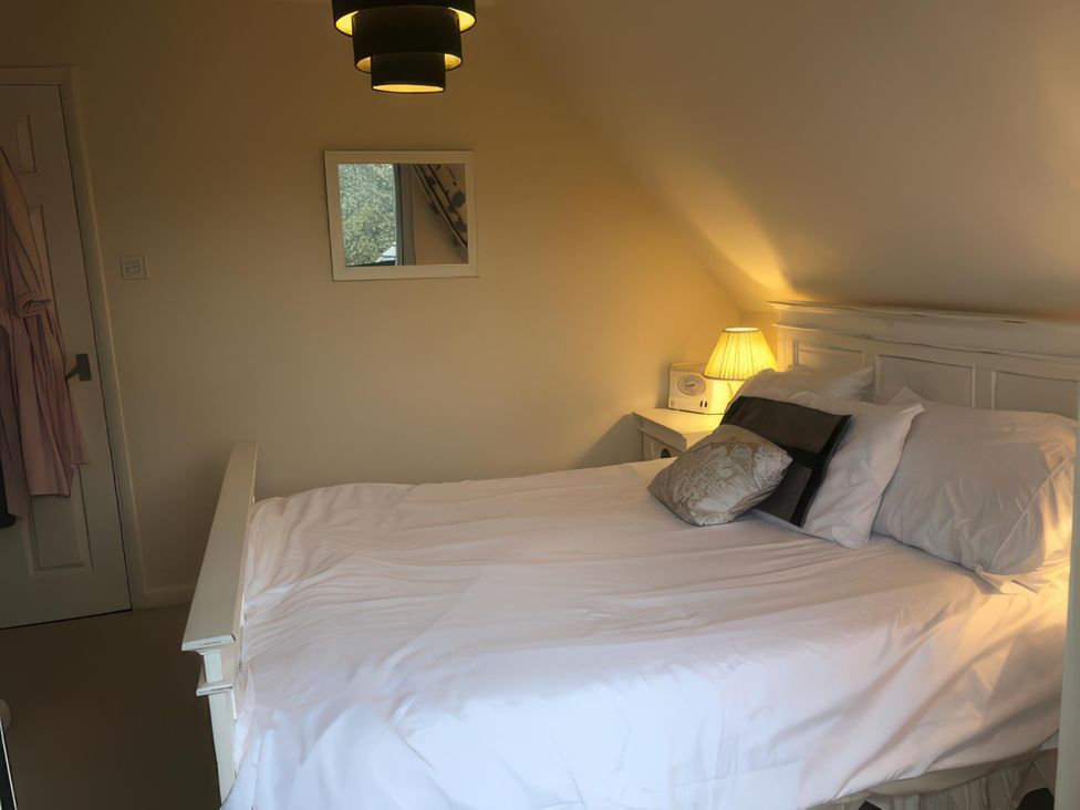 A bedroom with a bed and lamp at Cosy 3 Bedroom House on Cornish estate with pool in St Tudy