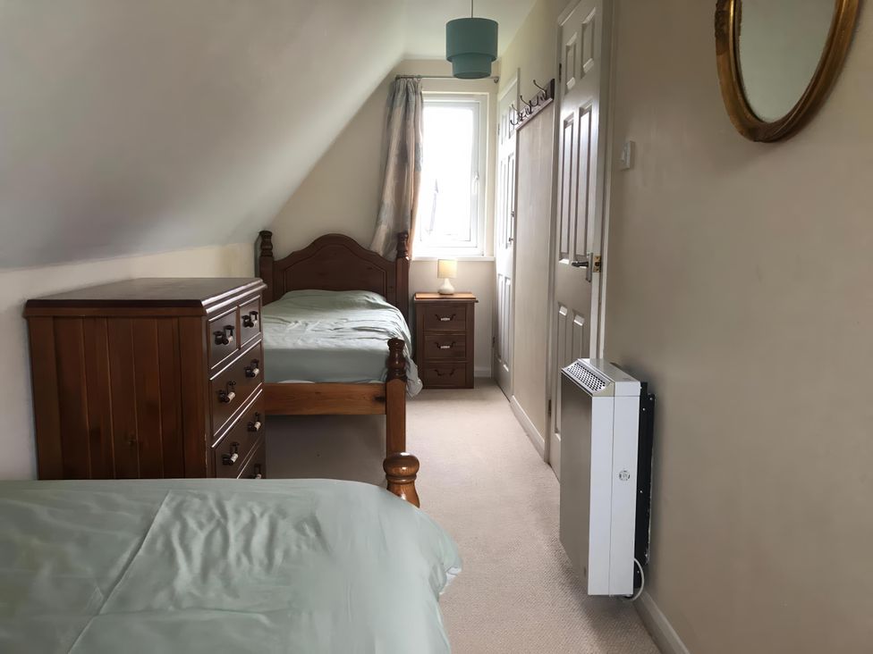 A bedroom with a bed, dresser, nightstand, and window at Cosy 3 Bedroom House on Cornish estate with pool in St Tudy