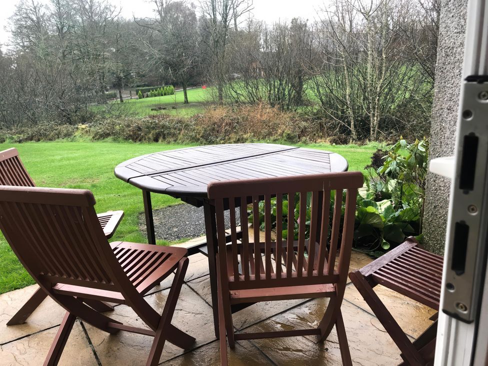 An outdoor patio area with a table and chairs at Cosy 3 Bedroom House on Cornish estate with pool, St Tudy