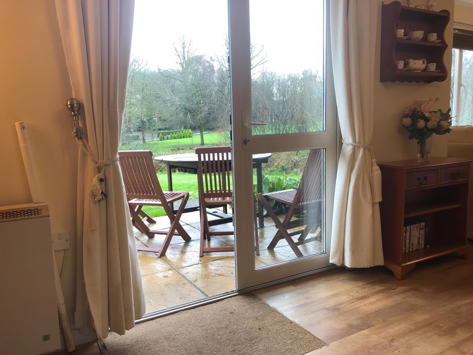 A living room with a door leading to an outdoor seating area at Cosy 3 Bedroom House on Cornish estate with pool St Tudy