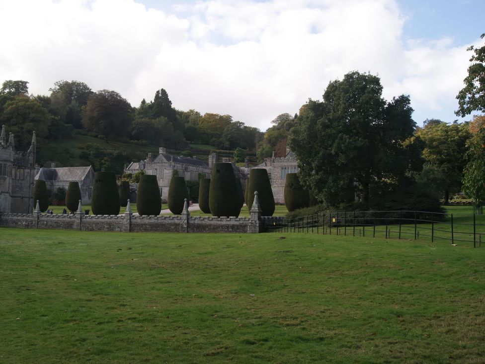 A landscape with trees, hedges, grass, and buildings at Cosy 3 Bedroom House on Cornish estate with pool, St Tudy