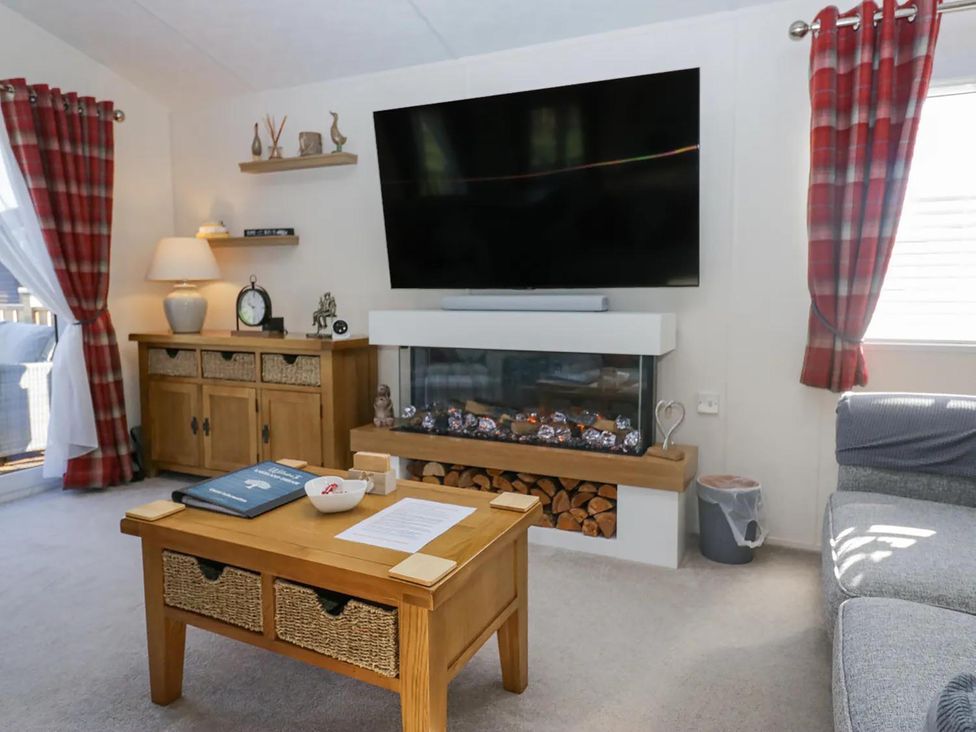 A living room with a sofa, television, and coffee table at Lakeland Lodge 3Bed 2 Bath Private Patio, Carnforth