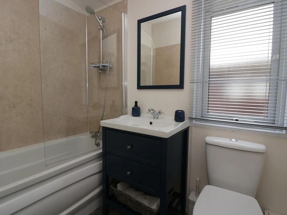 A bathroom with a bathtub, shower, and mirror at Lakeland Lodge 3Bed 2 Bath Private Patio, Carnforth
