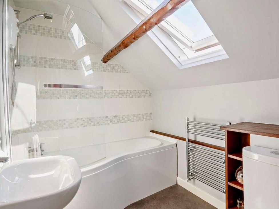 A bathroom with a bathtub, shower, wash basin, towel rail, and toilet at Cottage Sleeps 5 with Parking and Garden, Carreglefn