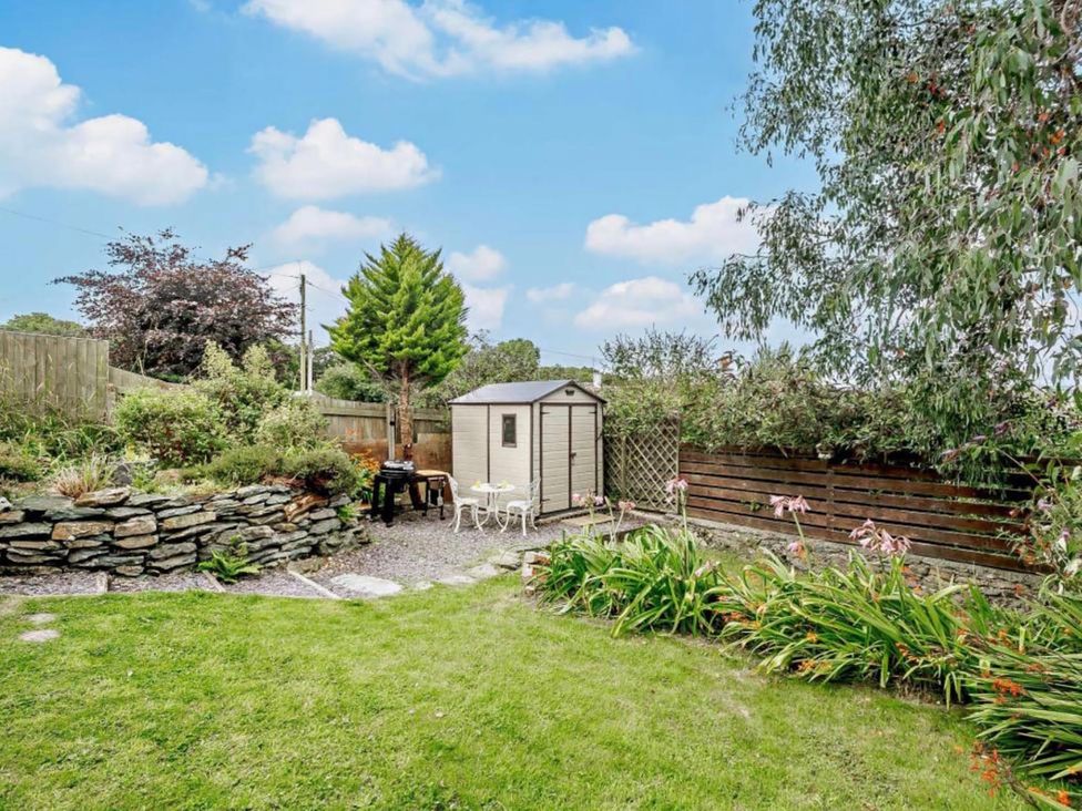 A garden with a shed, table, chairs, and flower bed at Cottage Sleeps 5 with Parking and Garden in Carreglefn