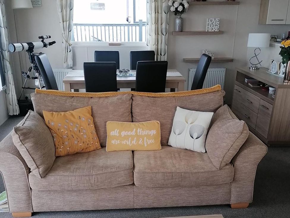 A living room with a sofa and dining area at Seaside Lodge Retreat in Eyemouth