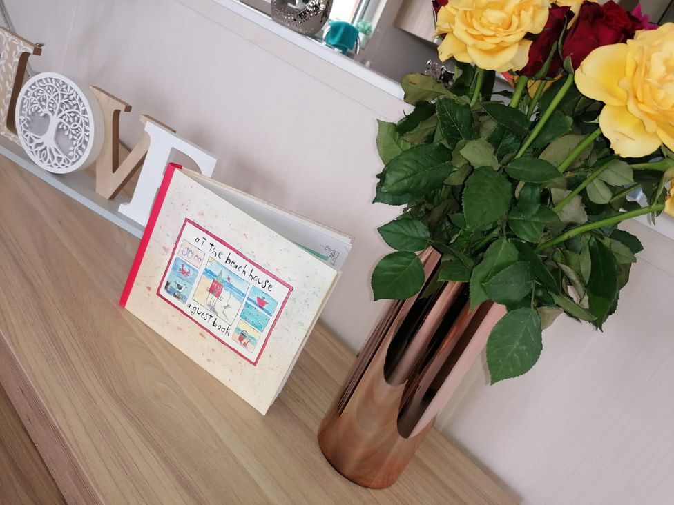 A book and flowers on a table at Seaside Lodge Retreat in Eyemouth