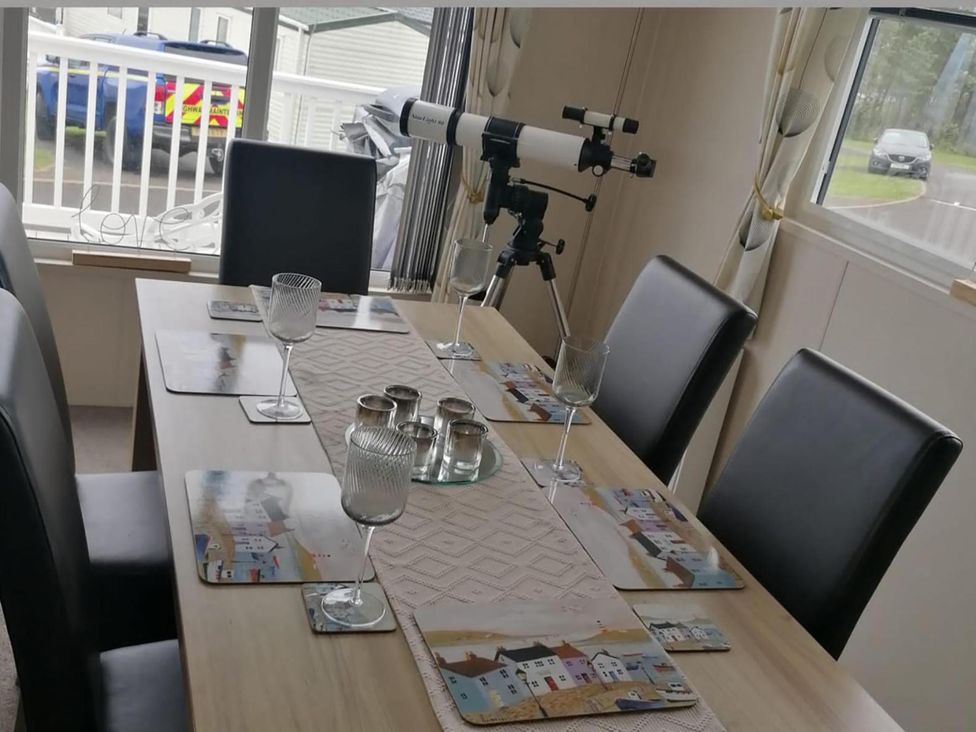 A dining room with a table and telescope at Seaside Lodge Retreat in Eyemouth