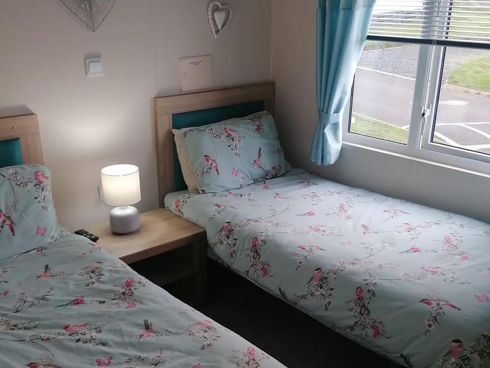 A bedroom with two beds and a lamp at Seaside Lodge Retreat in Eyemouth
