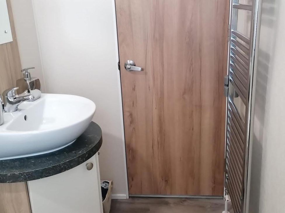 A bathroom with a sink and door at Seaside Lodge Retreat in Eyemouth
