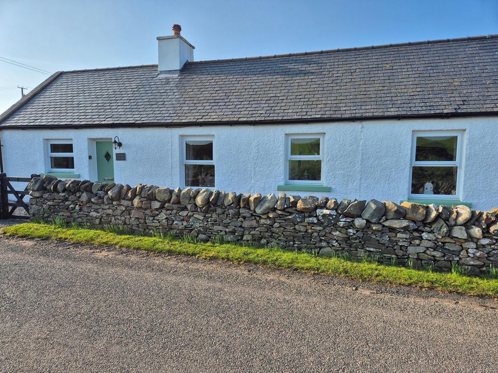 A house with a stone wall and windows at Beautiful 2Bed semi rural cottage enclosed garden Stranraer