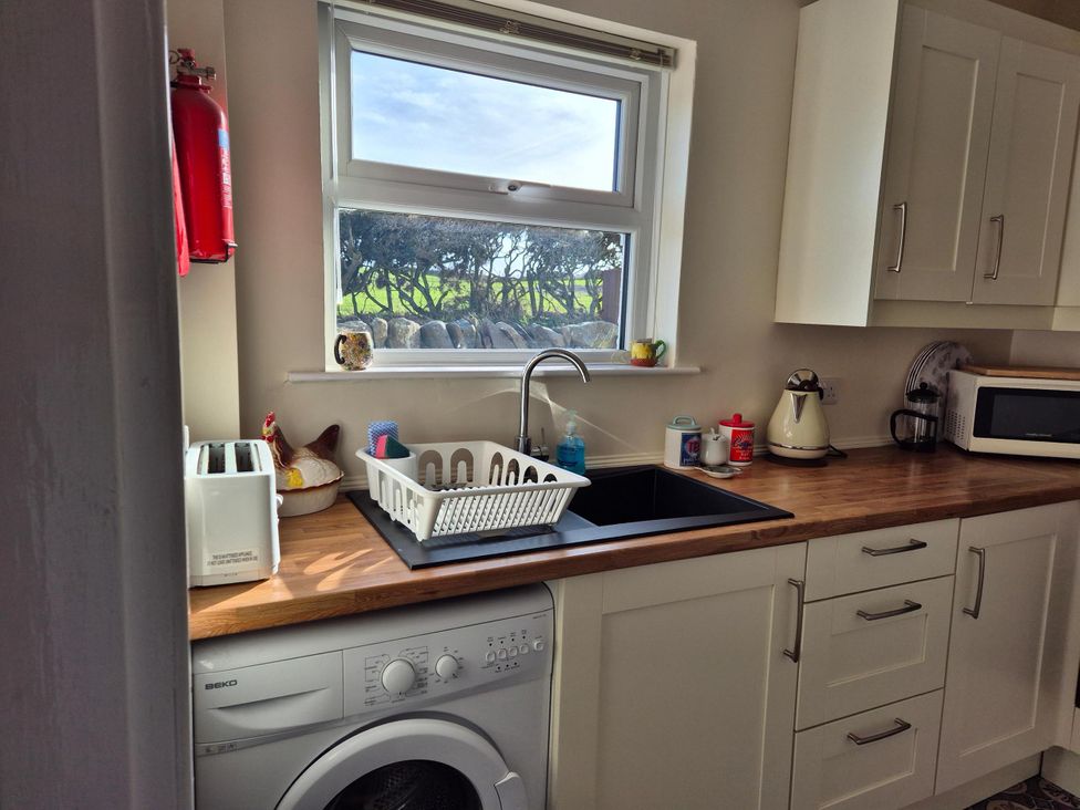A kitchen with a sink and washing machine at Beautiful 2Bed semi rural cottage enclosed garden Stranraer