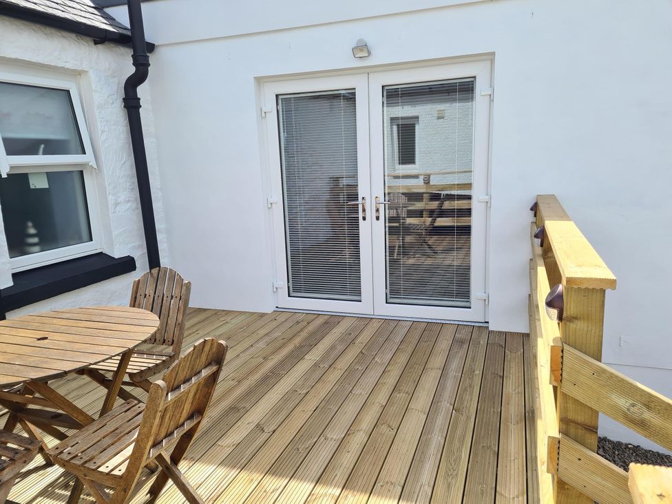 An outdoor terrace with a wooden deck and seating area at Beautiful 2Bed semi rural cottage enclosed garden in Stranraer