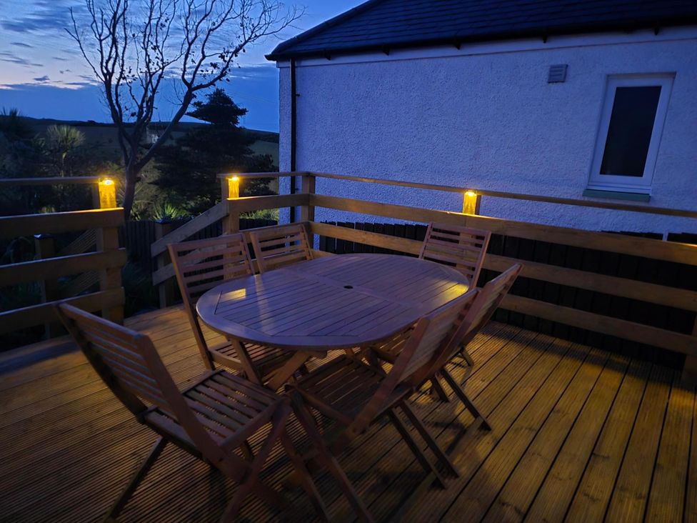 An outdoor dining area with a wooden table and chairs at Beautiful 2Bed semi rural cottage enclosed garden Stranraer