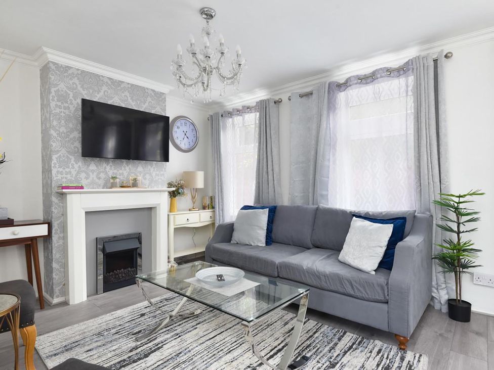 A living room with a sofa, television, and glass table at Suspire House Sleeps 6 Garden Bbq Coastal retreat Near Valley