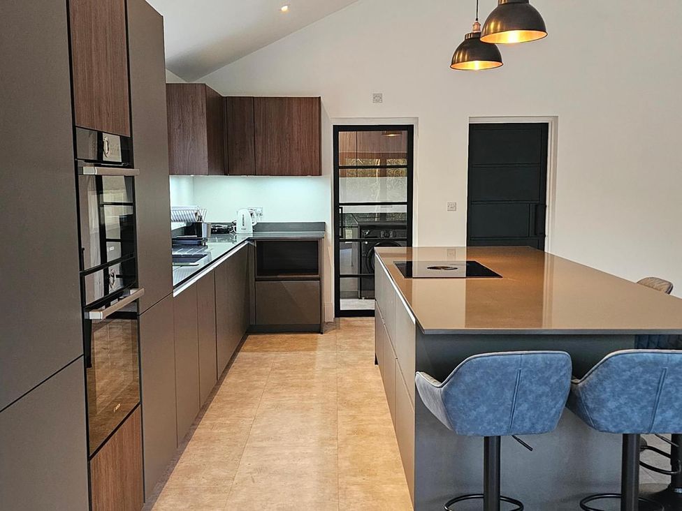 A kitchen with an island and stools at Luxury Kent Bungalow Retreat Sleeps 12 Cross-at-Hand near Staplehurst