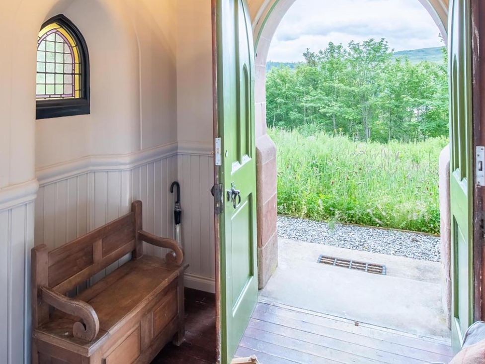 An entrance with a bench and door opening to an outdoor area at Grade C Church in Cannich