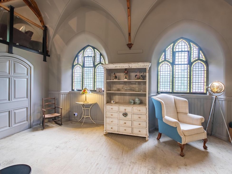 A living room with a cabinet and chair at Grade C Church in Cannich