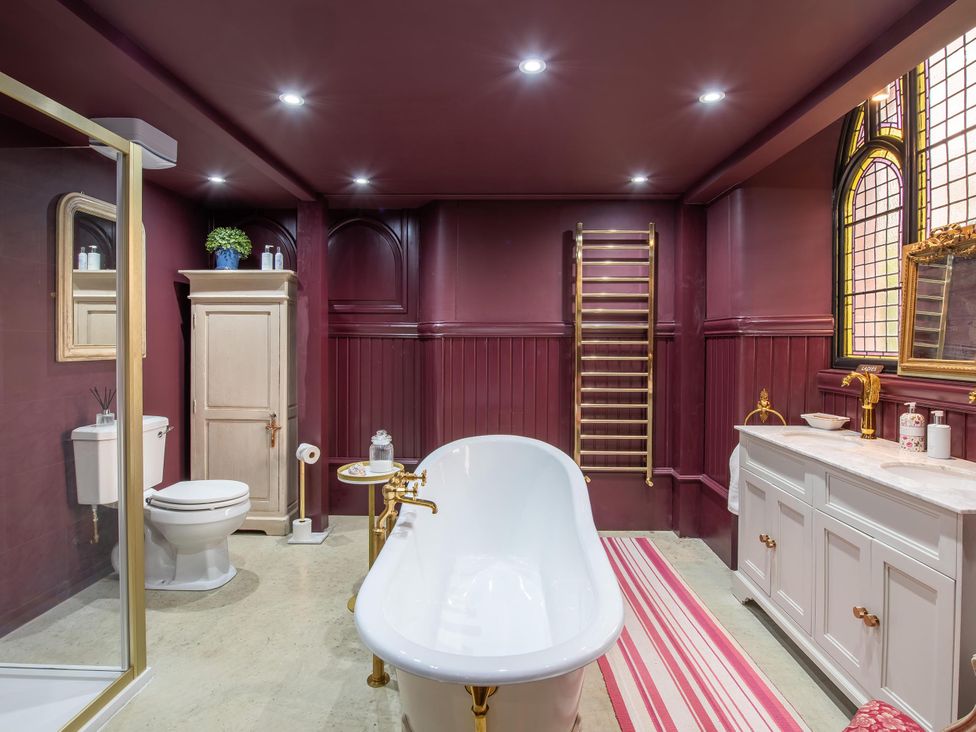 A bathroom with a bathtub, toilet, sink, and towel rack at Grade C Church in Cannich