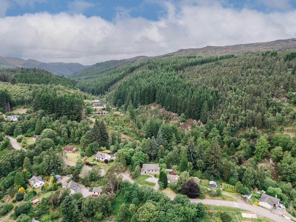 Aerial view of houses and trees in a forested area at Grade C Church in Cannich
