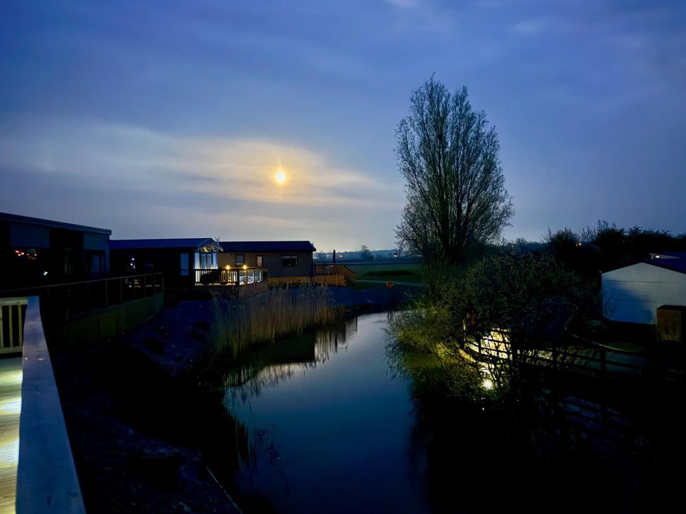 A view of lodges beside a river with a full moon at Malton 2Bed Lodge Sleeps 4 Pet Friendly in Malton