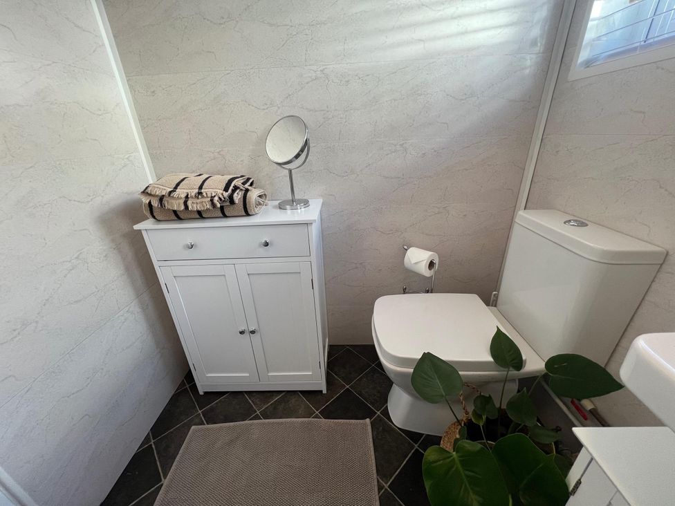 A bathroom with a toilet, cabinet, mirror and towels at The Old Barn in Manchester