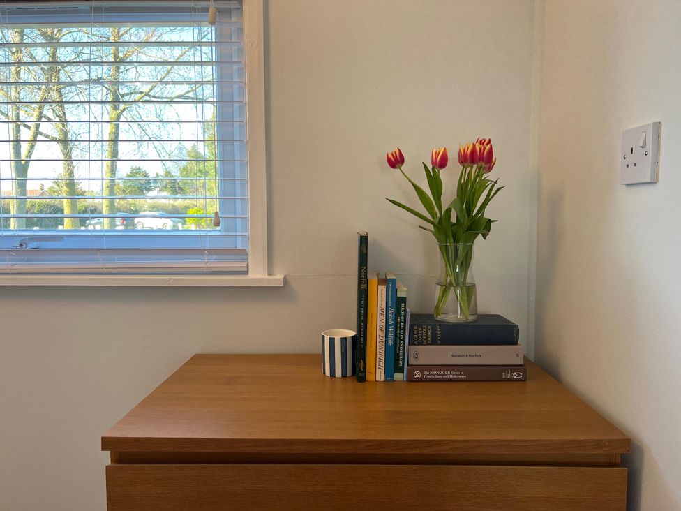 A table with books and a vase of flowers near a window at 