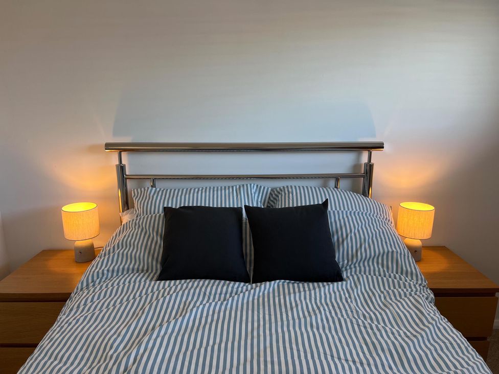 A bed with striped bedding and lamps on nightstands in the bedroom