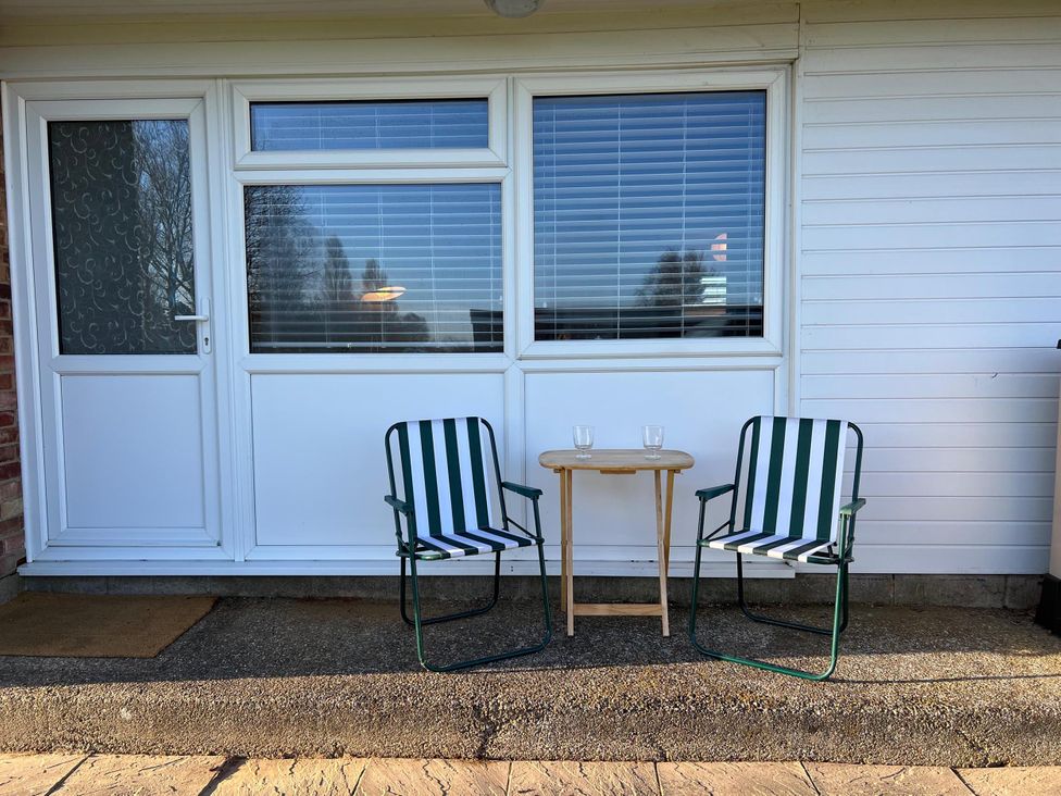 Two chairs and a table on a patio in front of a window at an outdoor area 