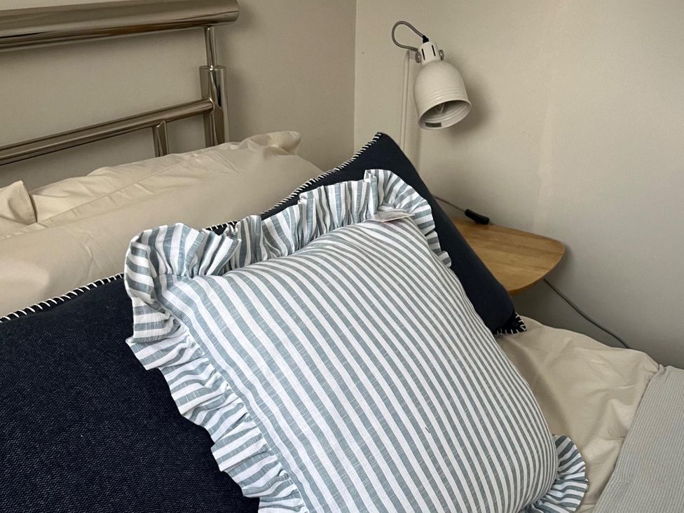 A bed with pillows and a lamp on a bedside table in a bedroom