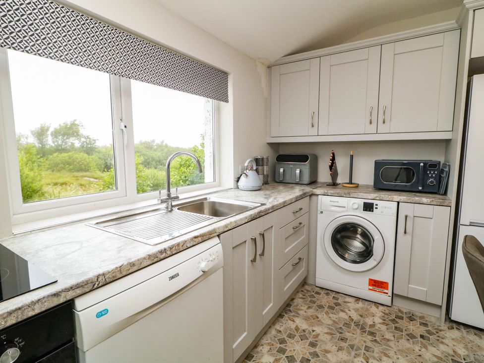 A kitchen with a sink, dishwasher, and washing machine at Biddy Granny's