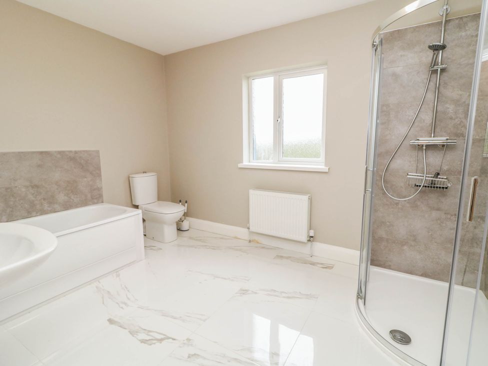 A bathroom with a bathtub, shower, and toilet at Biddy Granny's