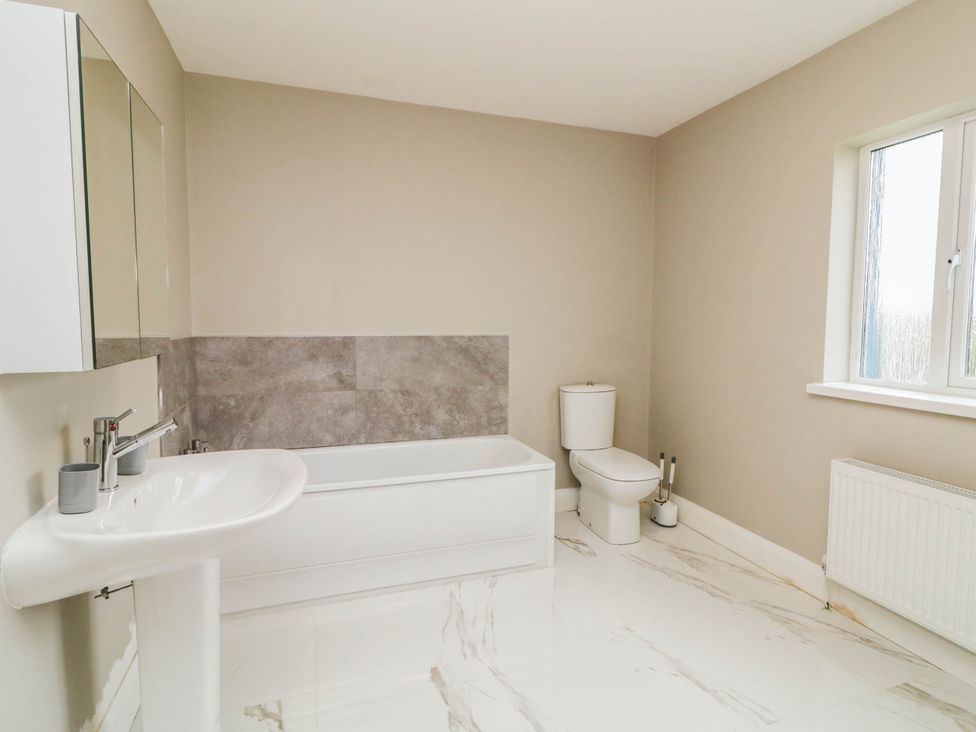 A bathroom with a bathtub, toilet, sink and window at Biddy Granny's 