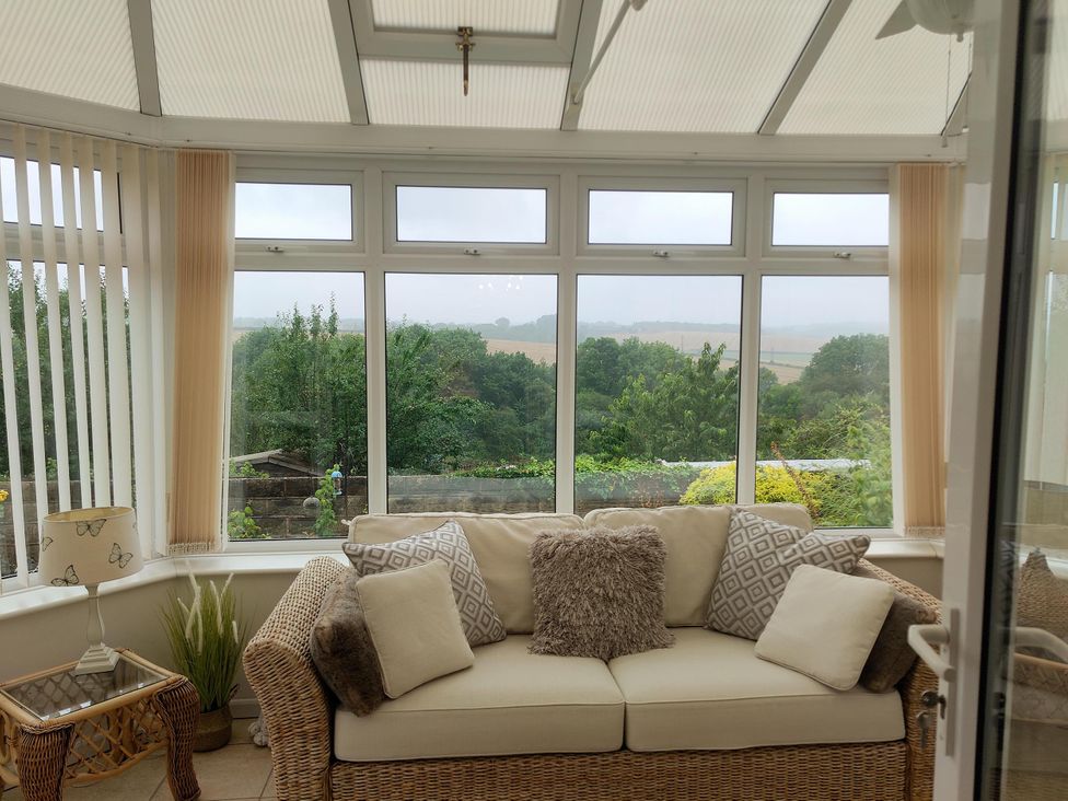 A conservatory with a sofa and lamp at Split Level Bungalow Sleeps4 Close to walks Stanton Hill