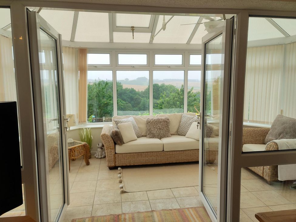 A conservatory with a couch and windows at Split Level Bungalow Sleeps4 Close to walks Stanton Hill
