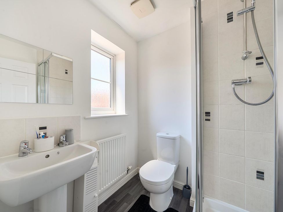 A bathroom with sink, toilet, shower, and mirror at House Sleeps 6 Enclosed Garden Pet Friendly in Bridgwater