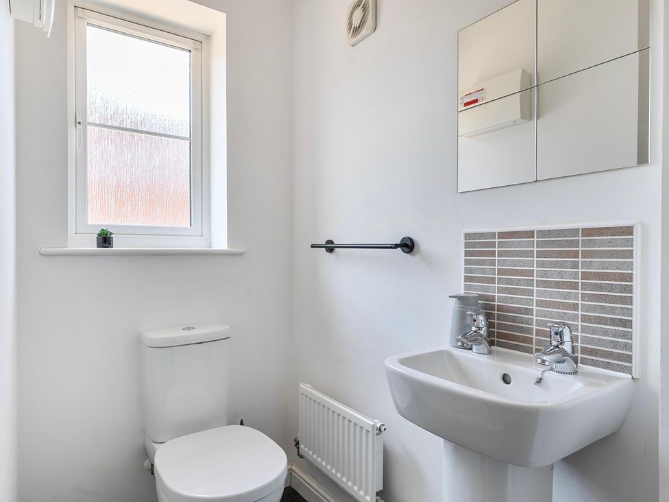 A bathroom with a toilet, sink, and mirror at House Sleeps 6 Enclosed Garden Pet Friendly Bridgwater