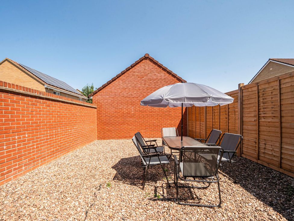 A garden with a table and chairs under an umbrella at House Sleeps 6 Enclosed Garden Pet Friendly in Bridgwater
