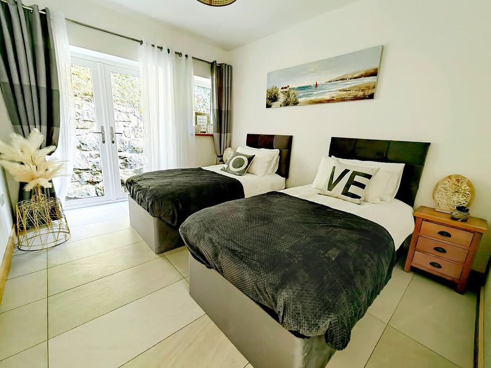 A bedroom with twin beds and a side table at 4 Bed Villa Sleeps 8 Private Terrace Free parking Near St Austell