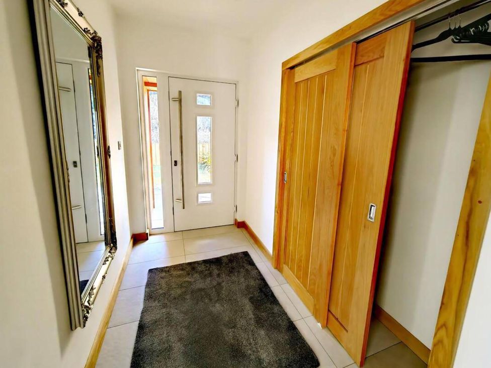 A hallway with a mirror and front door at 4 Bed Villa Sleeps 8 Private Terrace Free parking Near St Austell