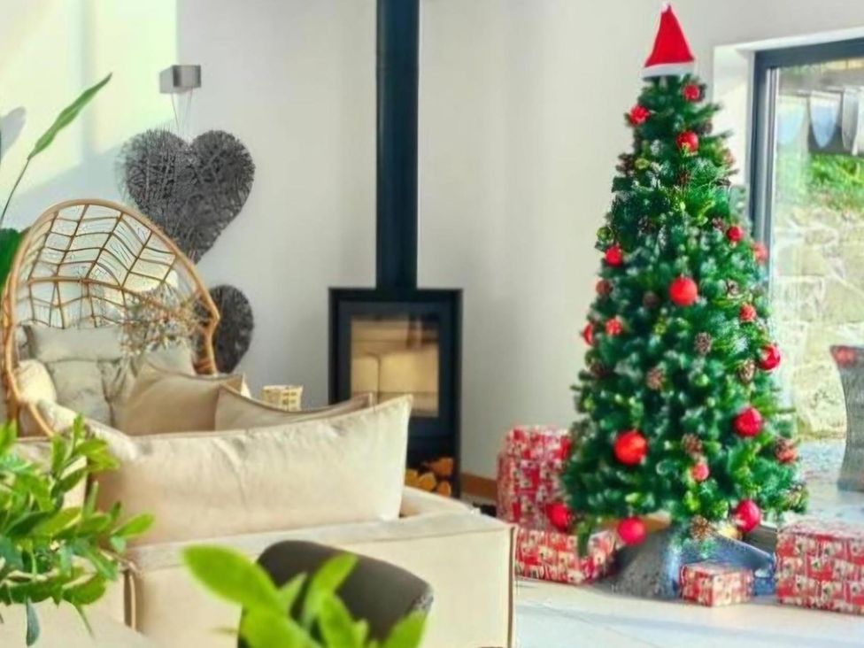 A living room with a Christmas tree and presents at 4 Bed Villa Sleeps 8 Private Terrace Free parking Near St Austell