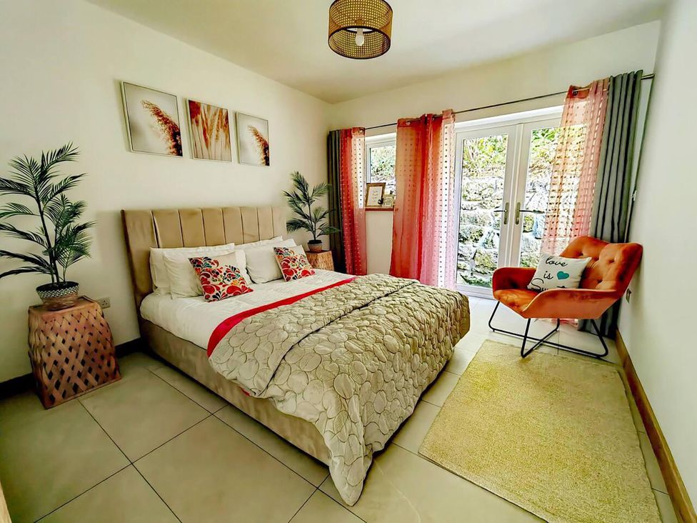 A bedroom with a bed and chair at 4 Bed Villa Sleeps 8 Private Terrace Free parking Near St Austell