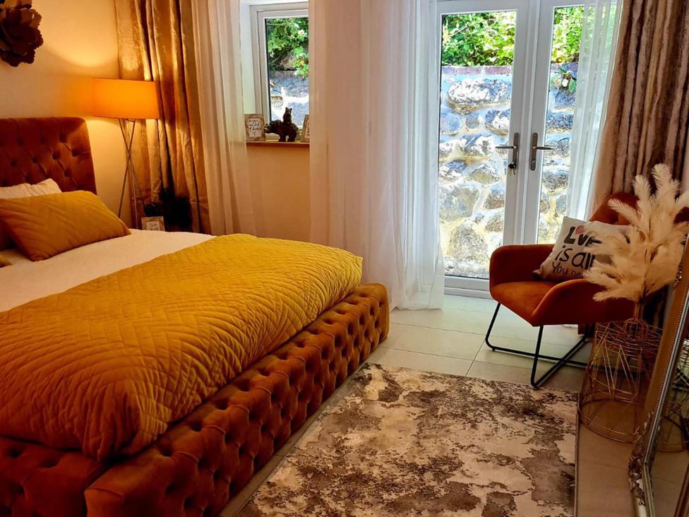 A bedroom with a bed and a chair at 4 Bed Villa Sleeps 8 Private Terrace Free parking Near St Austell