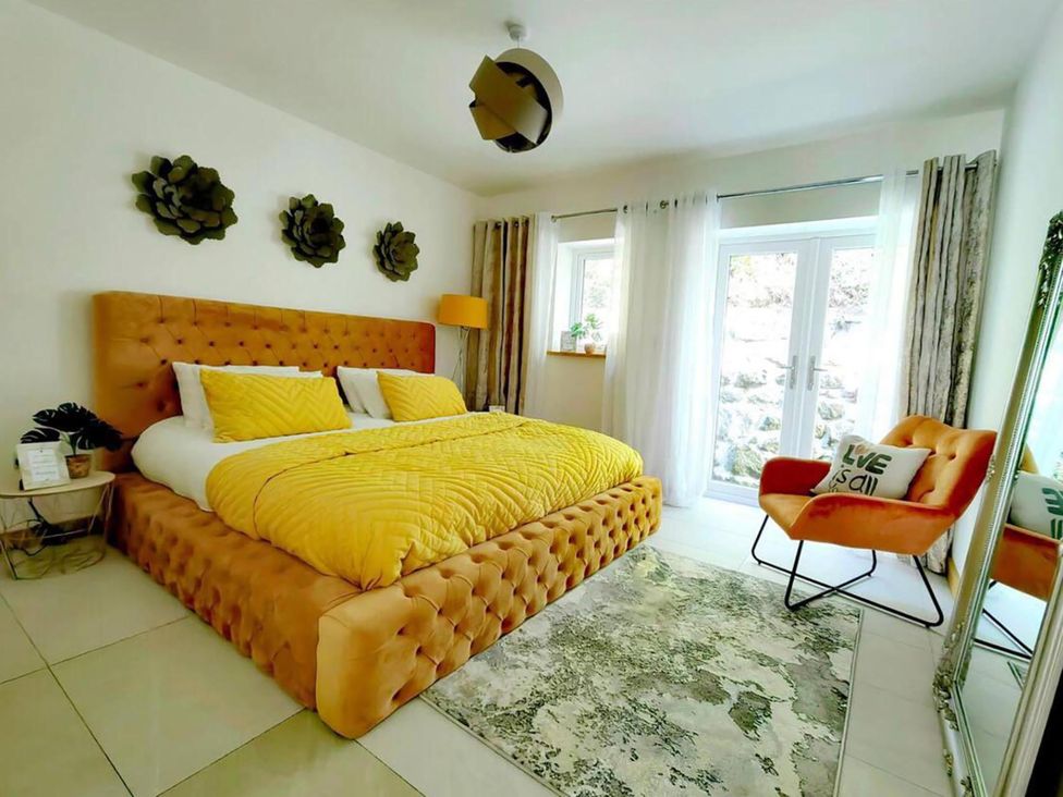 A bedroom with a yellow bed and an orange chair at 4 Bed Villa Sleeps 8 Private Terrace Free parking Near St Austell