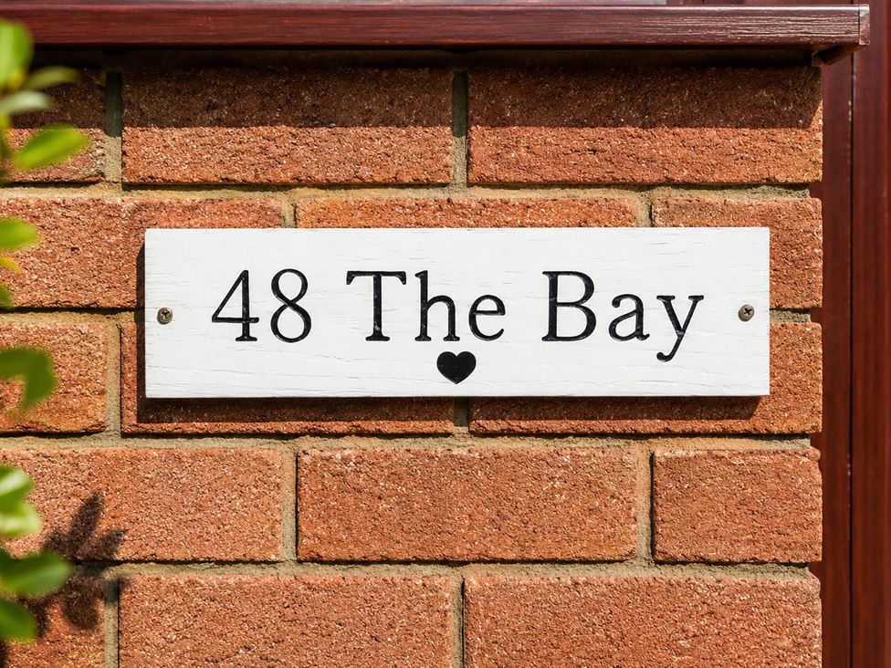 A sign displaying 48 The Bay on a brick wall at Coastal Chalet Retreat in St Margaret's Bay