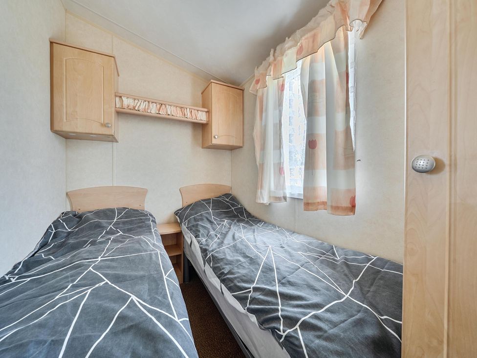 A bedroom with two single beds and a shelf above at 3 Bed Caravan Sleeps 8 Pets Garden Parking Hull