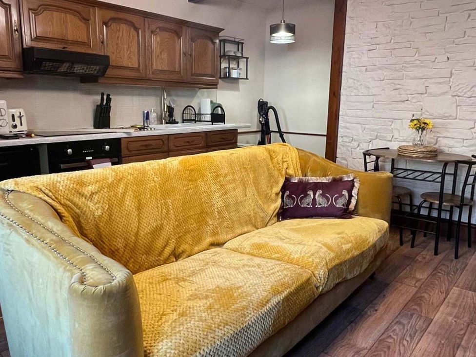 A living room with a yellow sofa and a kitchenette at Cozy Cottage Retreat near Haworth log burner, Keighley