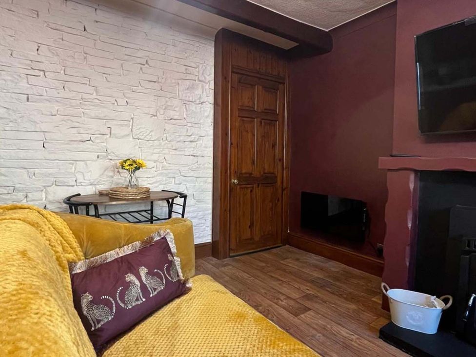 A living room with a sofa, table, door and television at Cozy Cottage Retreat near Haworth log burner, Keighley